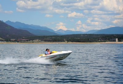 motor boat with people in it on a lake with mountains in the background